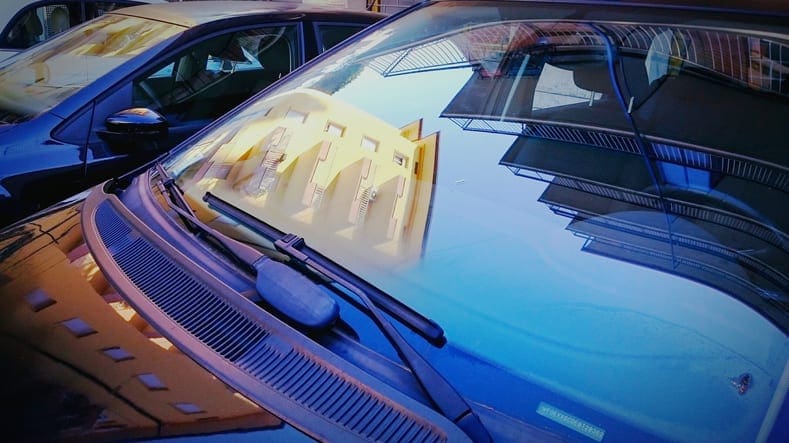 Buildings Sky Reflected In Parked Car Windshield